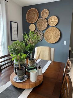 a dining room table with plates and plants on the wall above it, along with potted plants