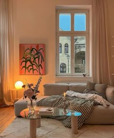 a living room filled with furniture next to a large window and a painting on the wall