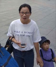 a woman and child walking down the street with luggage behind them, one carrying a cell phone