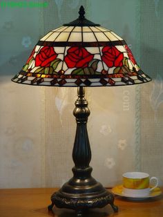 a table lamp sitting on top of a wooden table next to a cup and saucer