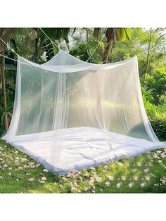 a white bed with mosquito netting hanging from it's sides in the middle of some flowers