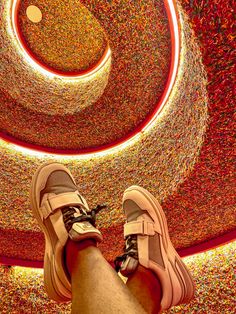 a person's feet standing in front of a colorful ceiling with circles and lights