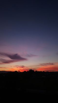 the sun is setting over some hills and trees