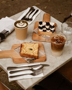 a table topped with plates and silverware next to cups filled with drinks, desserts and utensils