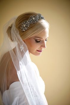 a woman wearing a veil with a tiara on her head and hair comb in her hand