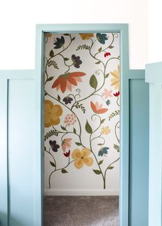 an open door with colorful flowers painted on the wall and behind it is a carpeted floor