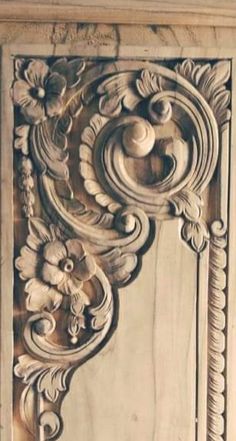 an intricately carved wooden panel with flowers and leaves on the front side of it