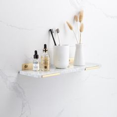 three white vases are sitting on a shelf next to some bottles and other items