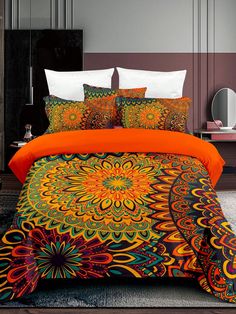 a bed with an orange comforter and two pillows on top of it in front of a mirror