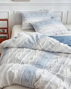 an unmade bed with blue and white comforter