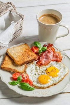 a white plate topped with eggs and toast next to a cup of coffee