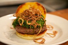 a hamburger with onion rings on it sitting on a plate