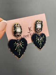 a pair of black heart shaped earrings on top of a card