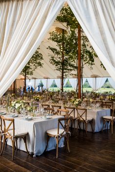 the tables are set with white linens and place settings for an outdoor wedding reception