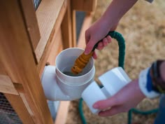 a person pouring water into a cup from a hose