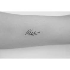 a black and white photo of a person's arm with a small tattoo on it