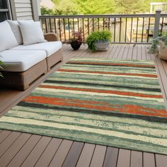 an outdoor area rug on a deck with couches and potted plants in the background