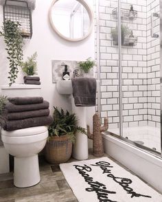 a white toilet sitting next to a bath tub in a bathroom under a round mirror