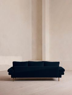 a blue couch sitting on top of a hard wood floor next to a white wall