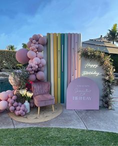 a birthday decoration with balloons and flowers on the ground next to a sign that says happy birthday