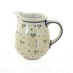 a white pitcher with blue and green designs on the bottom is sitting against a white background