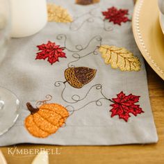 the table is decorated with autumn leaves and acorns on linen placemats