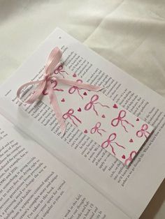 an open book with pink ribbon and scissors on it