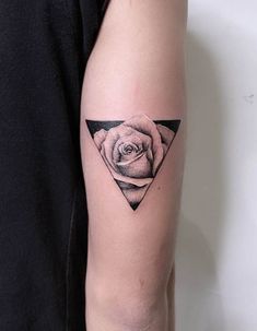 a black and white rose tattoo on the left upper arm, with an inverted triangle behind it