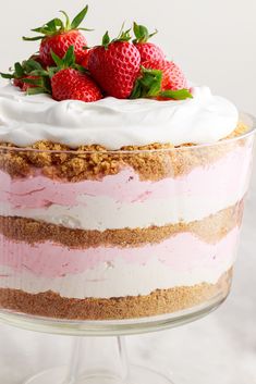 a cake with strawberries on top and frosting in the middle is sitting on a glass pedestal