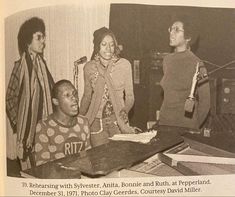 an old black and white photo of people around a table with books on it,