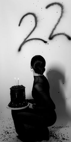 a woman kneeling down with a cake in front of her and the number twenty two written on it