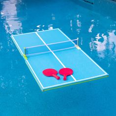 two ping pong paddles laying on top of a blue pool