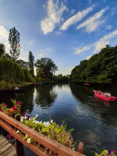 a red boat floating on top of a river next to lush green trees