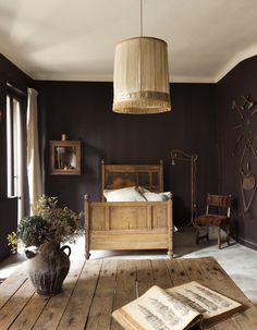 a bedroom with a bed, table and lamp in the corner next to an open book