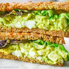 a sandwich with avocado and lettuce on it is cut in half