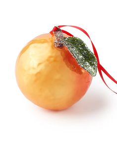 an orange ornament with a green leaf on it's top and red ribbon