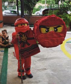 a child dressed up as a ninja holding a red paper bag with two faces on it