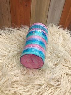 a pink and blue tube sitting on top of a white furry rug next to a wooden wall