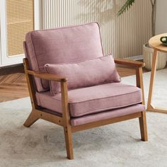 a pink chair sitting on top of a white rug next to a table with a plant