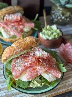 two sandwiches with meat, lettuce and sauces on them sitting on plates