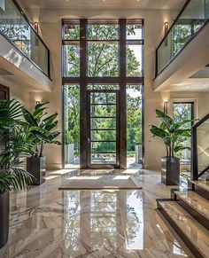 a large foyer with marble floors and high windows, surrounded by potted greenery