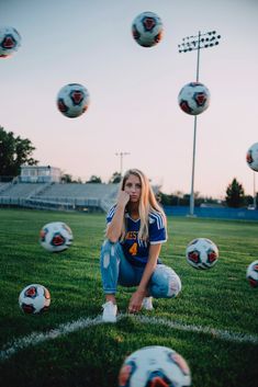 a woman sitting on the ground with soccer balls in the air above her and behind her she is looking at the camera