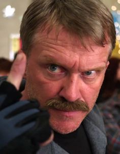 a man with a mustache and gloves on