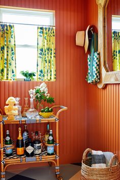 a table with bottles and glasses on it in front of a window next to a mirror