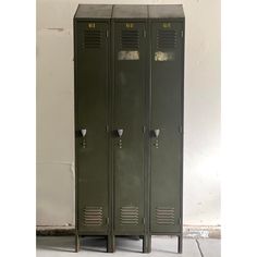 two green lockers sitting next to each other on the floor in front of a white wall