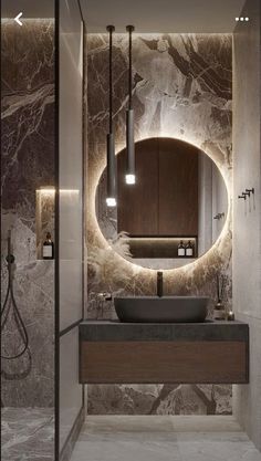 a bathroom with marble walls and flooring, round mirror on the wall above the sink