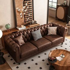 a brown leather couch sitting in a living room next to a coffee table and lamp