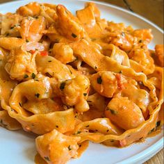 a white plate topped with pasta covered in sauce and cheese toppings on top of a wooden table