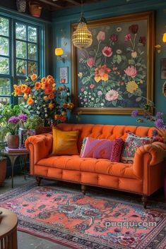 an orange couch sitting in front of a painting on the wall next to potted plants