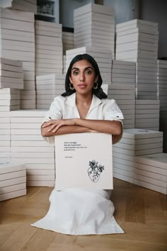 a woman sitting on top of a pile of white boxes with her arms folded over her chest